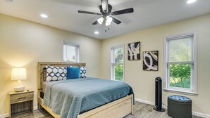 Une chambre à coucher comprenant un lit, une table de chevet, une commode et un ventilateur de plafond.