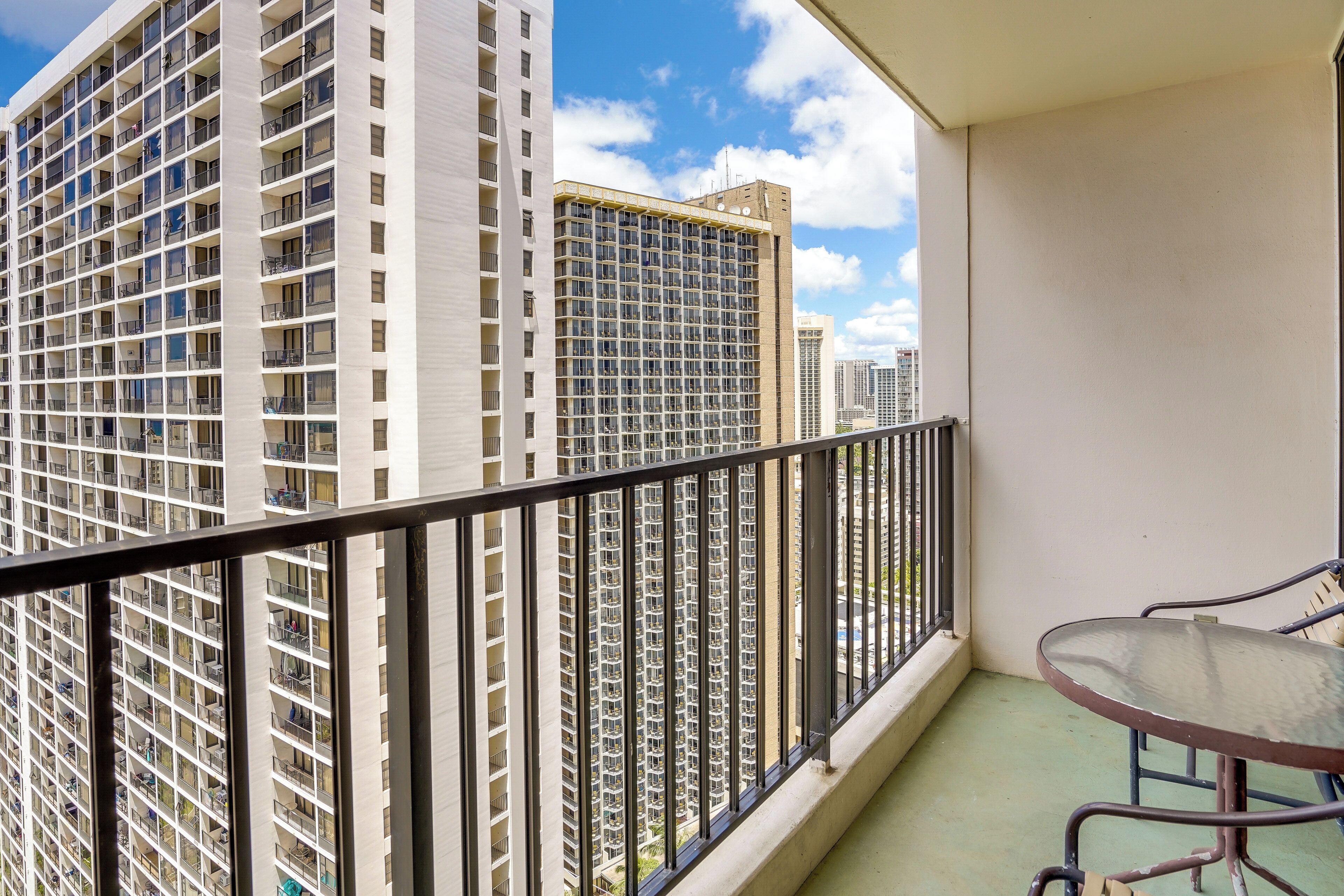 A balcony with a metal railing, a small table, and chairs.