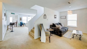 Ein geräumiges Wohnzimmer mit Treppe, Sofa, Couchtisch und Essbereich.