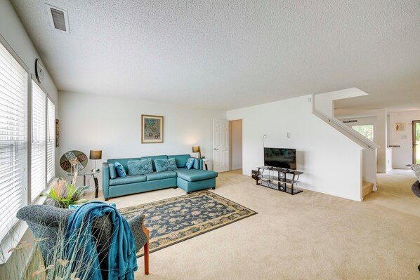 A living room with a teal sofa, a patterned rug, a television, and a staircase leading to another level. - 3 Living Areas & Community Pool: Camby Retreat (Camby)