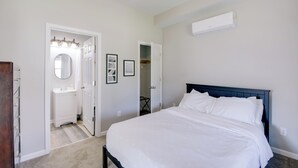 A bedroom with a bed, a white wall, a ceiling fan, and a white air conditioning unit. - Indianapolis Home w/ Porch - Close to Mile Square! (Indianapolis)