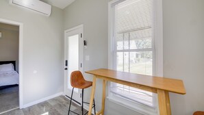 A room with a wooden table and two chairs, a door with a lock, and a window with blinds. - Indianapolis Home w/ Porch - Close to Mile Square! (Indianapolis)