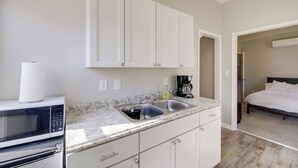 A kitchen with white cabinets, a stainless steel sink, a microwave, and a coffee maker. - Indianapolis Home w/ Porch - Close to Mile Square! (Indianapolis)