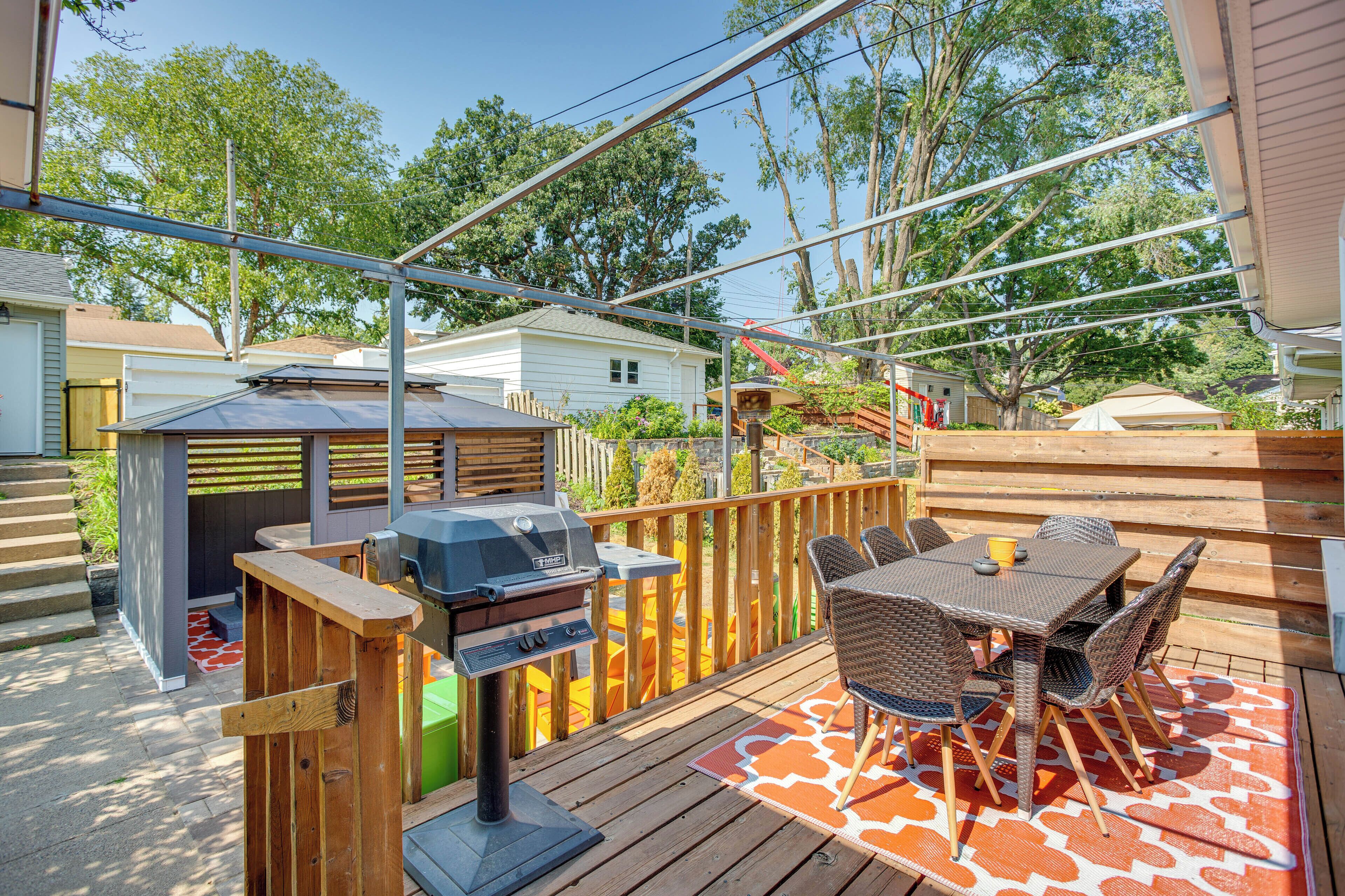A deck with a grill, outdoor furniture, and a view of neighboring houses.
