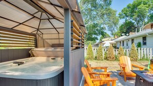 Un área de hidromasaje al aire libre con sillas de madera y una parrilla.