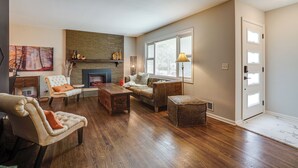 Una sala de estar con chimenea, un sofá, un sillón y una mesa de centro.