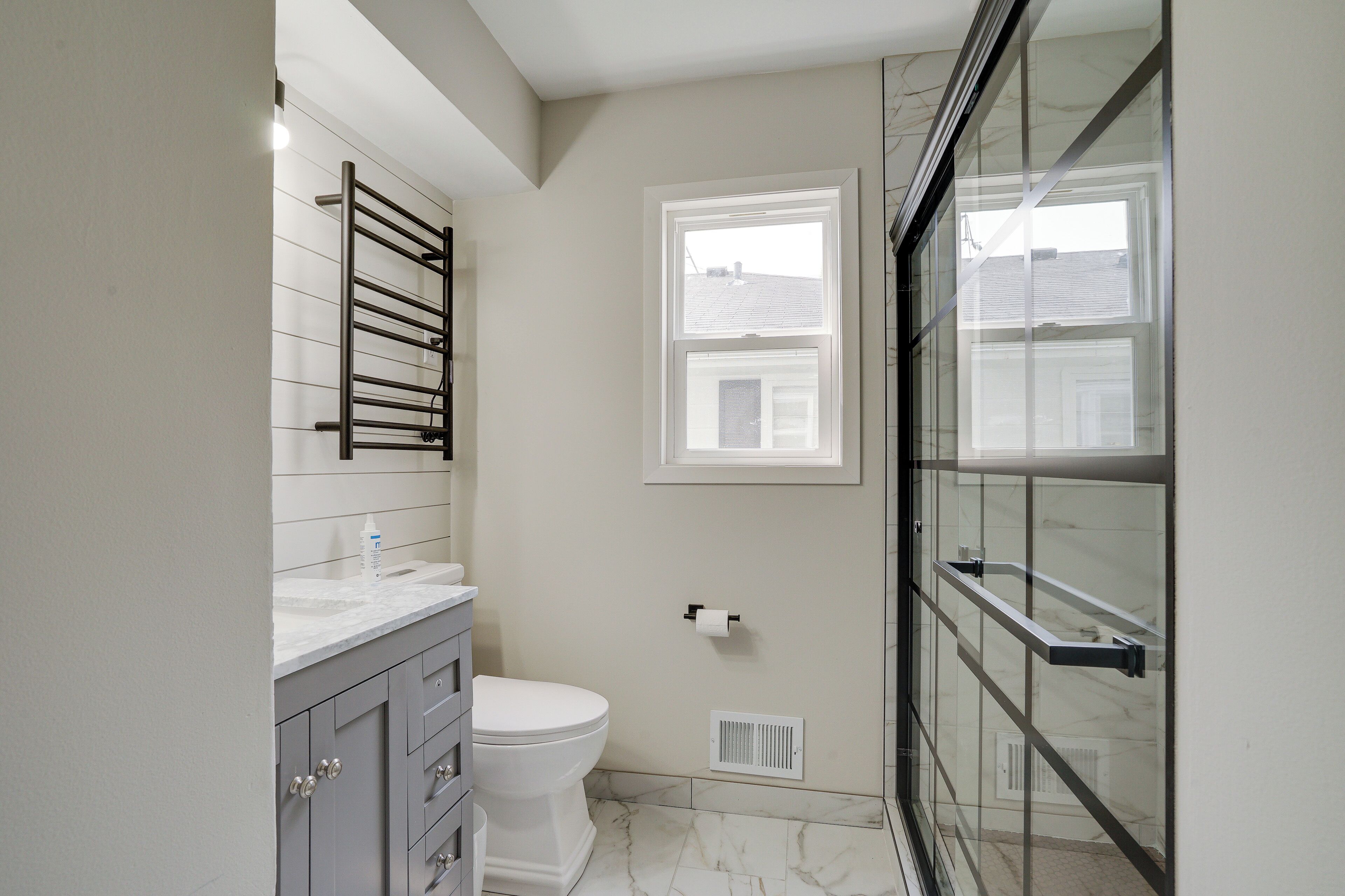 Une salle de bain moderne équipée de toilettes, d’un meuble-lavabo et d’une douche à parois de verre.