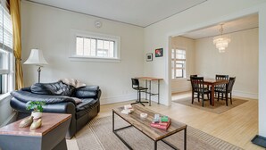 Una sala moderna con un sofá de cuero, una mesa de centro de madera y un comedor con una mesa y sillas de madera.