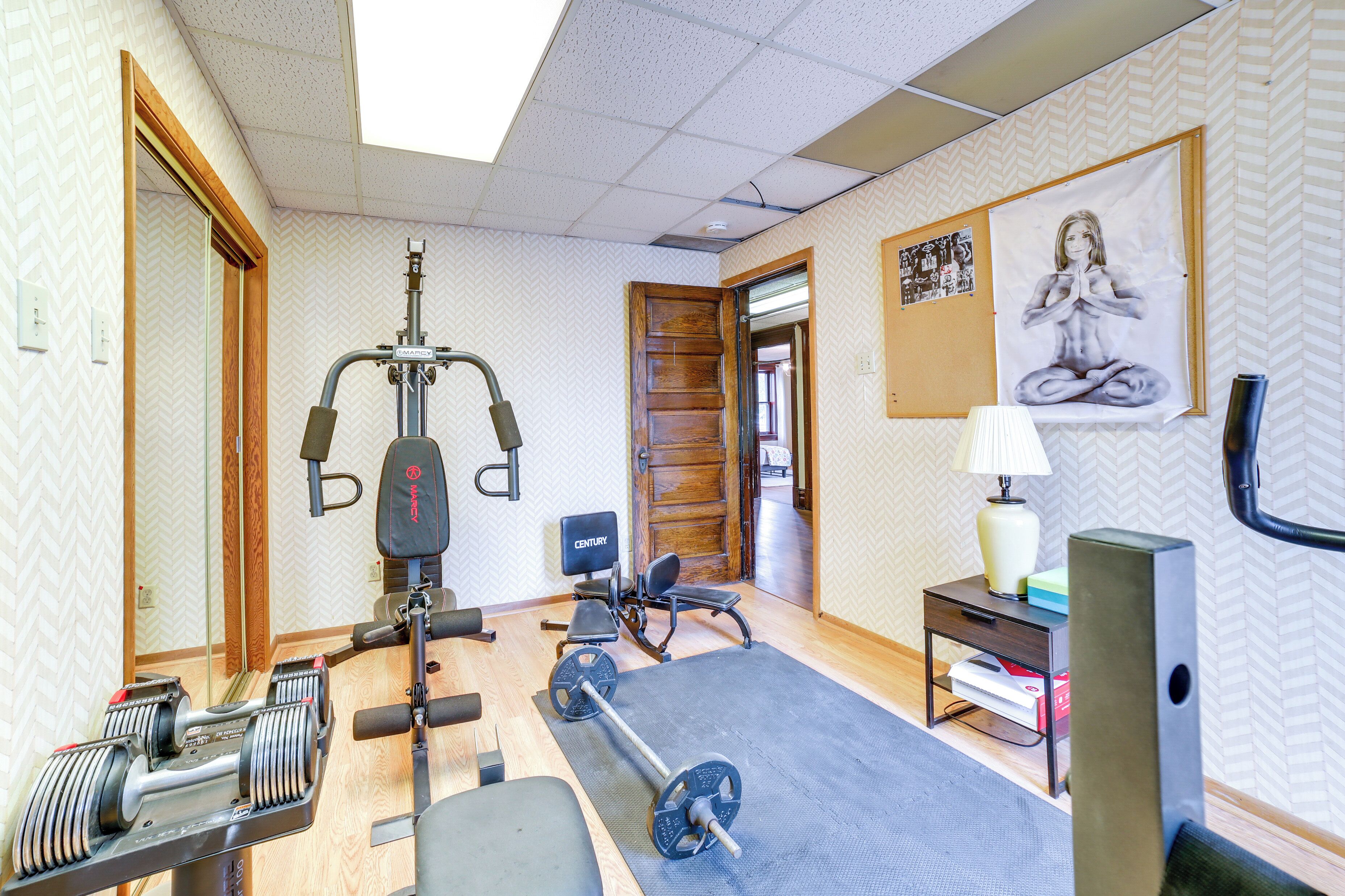 A gym with exercise equipment, a yoga mat, and a poster on the wall.