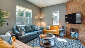 A living room with a blue sofa, a yellow sofa, a round coffee table, and a fireplace. - Family-friendly Shadyside Gem Near Dtwn Pittsburgh (Pittsburgh)