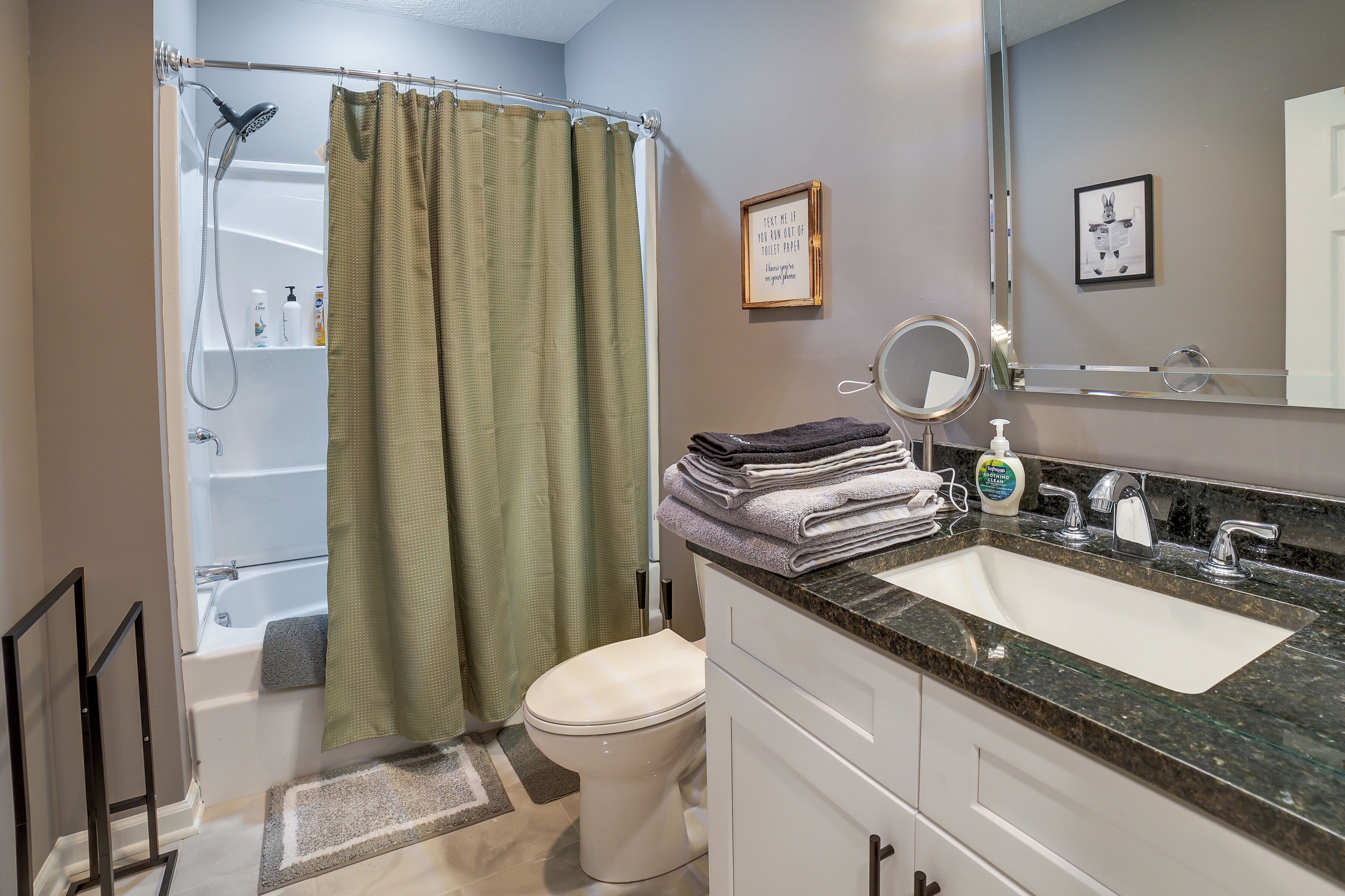 A bathroom with a shower, toilet, sink, and a mirror.