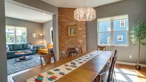 A dining area with a long wooden table, a colorful leaf-patterned runner, and a brick wall. - Family-friendly Shadyside Gem Near Dtwn Pittsburgh (Pittsburgh)