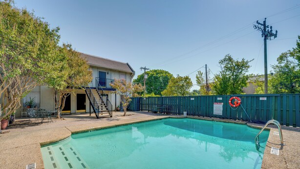 A swimming pool with a lifebuoy, a covered patio area, and a fenced yard. - Dallas Vacation Rental Condo w/ Community Pool! (Dallas)