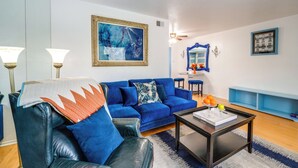 A living room with a blue sofa, a coffee table, and a painting on the wall. - Dallas Vacation Rental Condo w/ Community Pool! (Dallas)