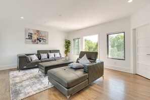 Uma sala de estar moderna com sofá seccional, chaise longue e uma janela grande que oferece luz natural.