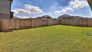 A backyard with a wooden fence, a lawn, and houses in the background. - Houston Home w/ Private Yard - 16 Mi to Dtwn (Houston)