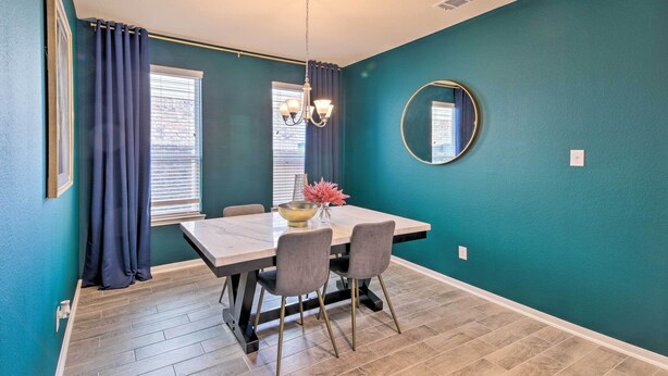 A dining area with a table, chairs, a chandelier, and a mirror on teal walls. - Houston Home w/ Private Yard - 16 Mi to Dtwn (Houston)