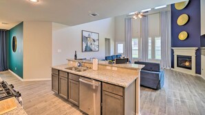 A modern kitchen with a central island, a dining area with a sofa, and a fireplace. - Houston Home w/ Private Yard - 16 Mi to Dtwn (Houston)