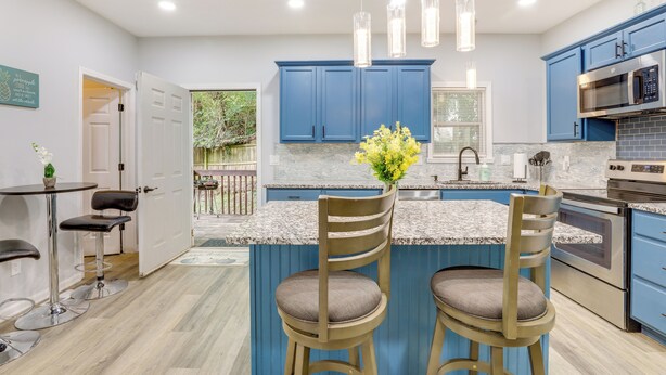 A modern kitchen with blue cabinets, a central island with two bar stools, stainless steel appliances, and pendant lighting. - Ideal ATL Base 2 Mi to Mercedes-benz Stadium, Dtwn (Atlanta)