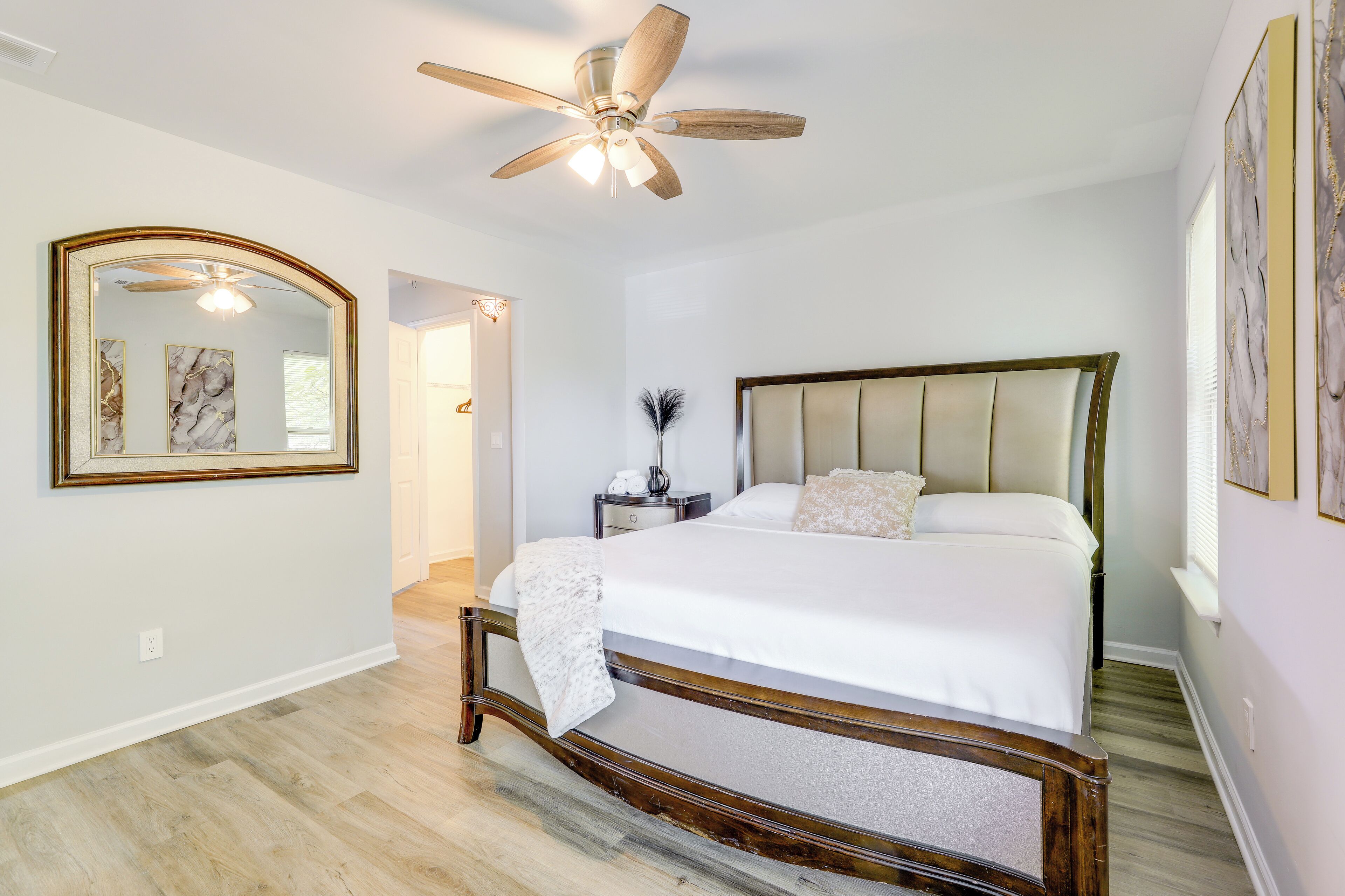 Un dormitorio con cama, ventilador de techo, mesita de noche y espejo.