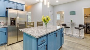 A modern kitchen with blue cabinets, a stainless steel refrigerator, a granite countertop, and pendant lighting. - Ideal ATL Base 2 Mi to Mercedes-benz Stadium, Dtwn (Atlanta)