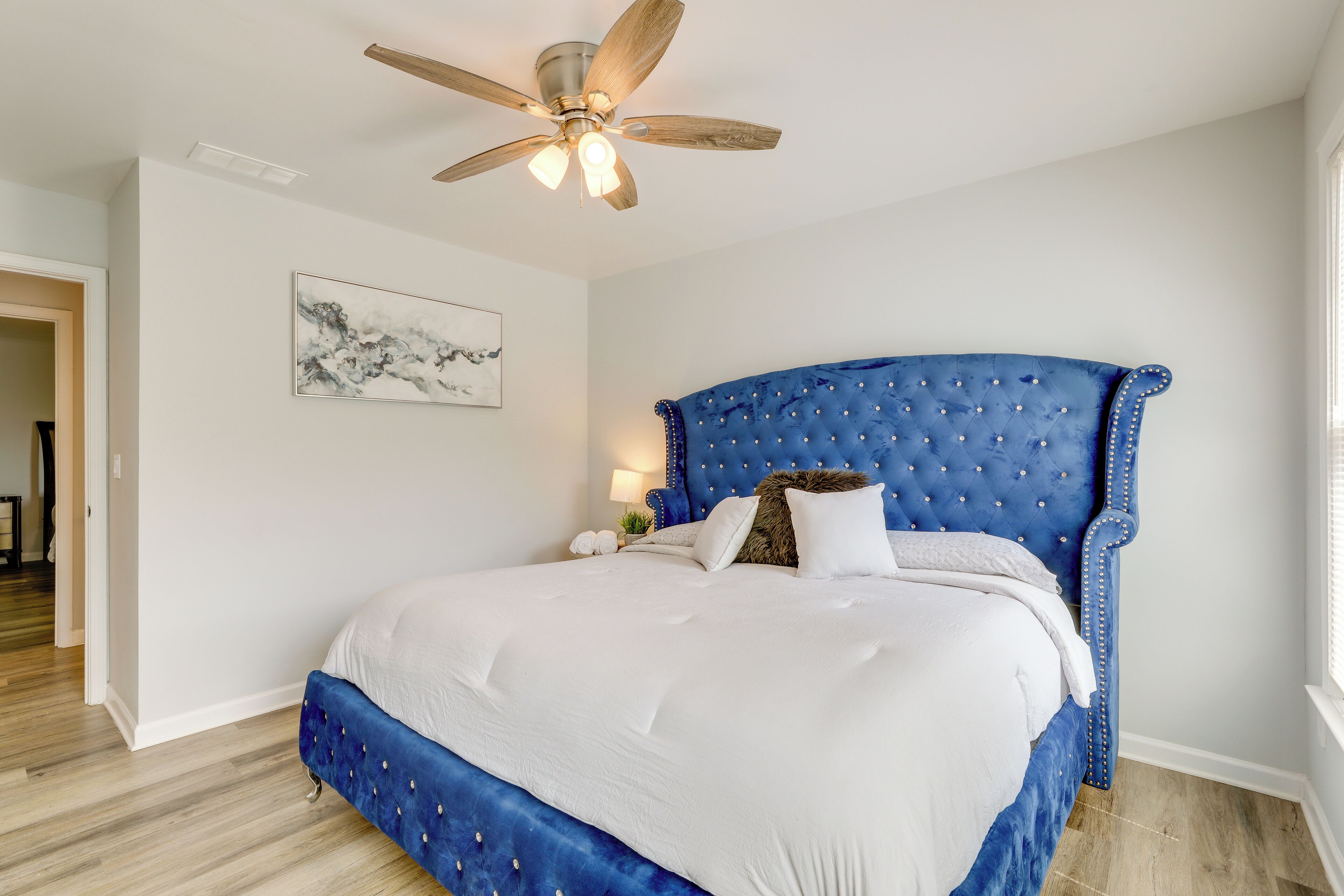 Ein Schlafzimmer mit einem großen Bett, einem Deckenventilator und einem Gemälde an der Wand.