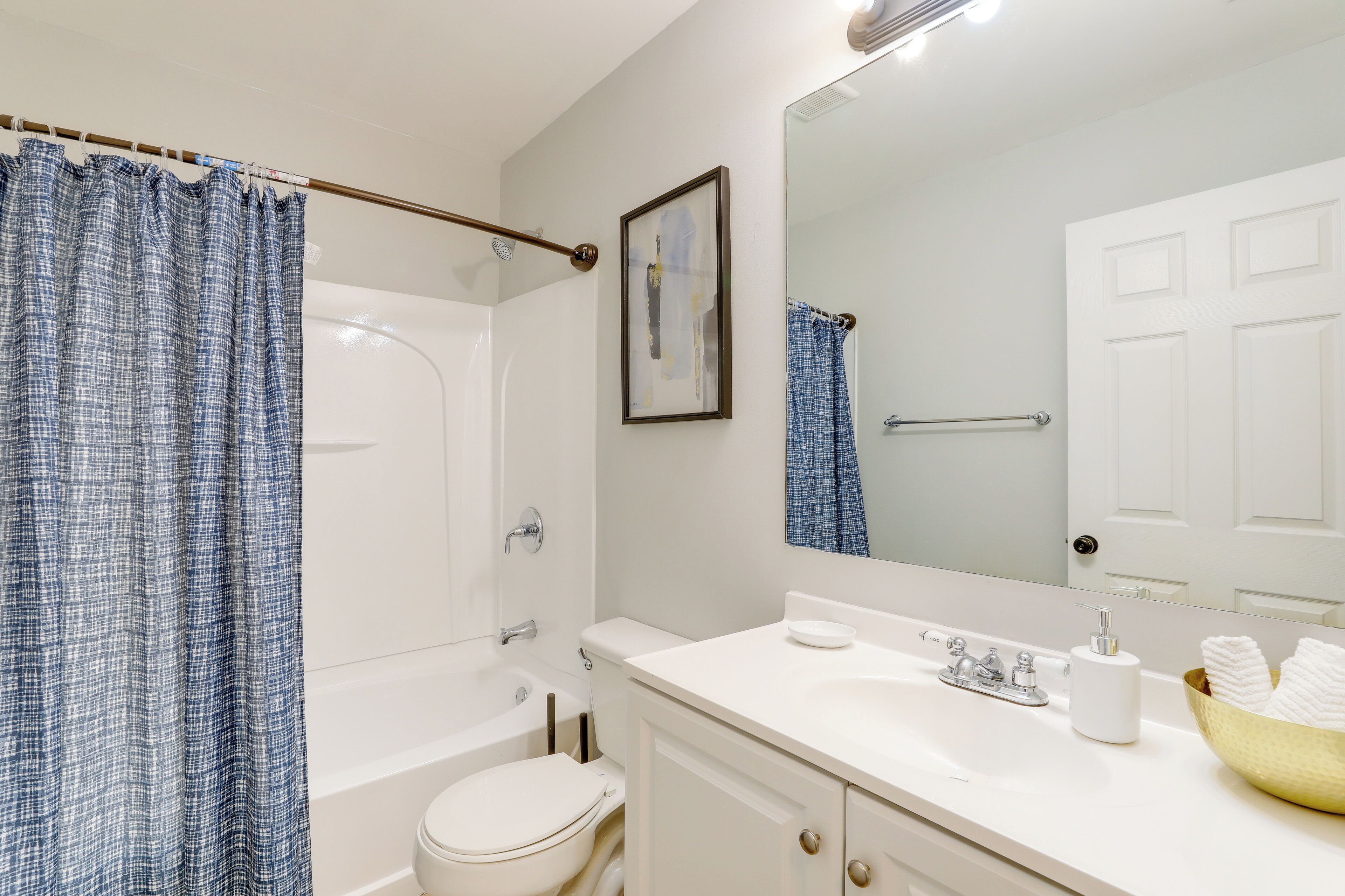 Un bagno con il water bianco, una vasca, un lavandino con specchio e un appendi asciugamani.