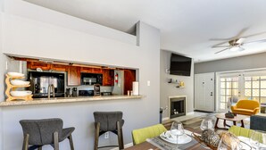 A modern kitchen with a bar area, a dining table set for four, and a living area with a sofa and chairs. - Houston Rental in Gated Community w/ Pool Access! (Houston)