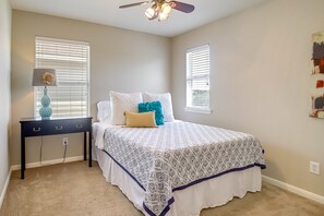 Relax in this serene bedroom with a large bed, nightstand, and ceiling fan.