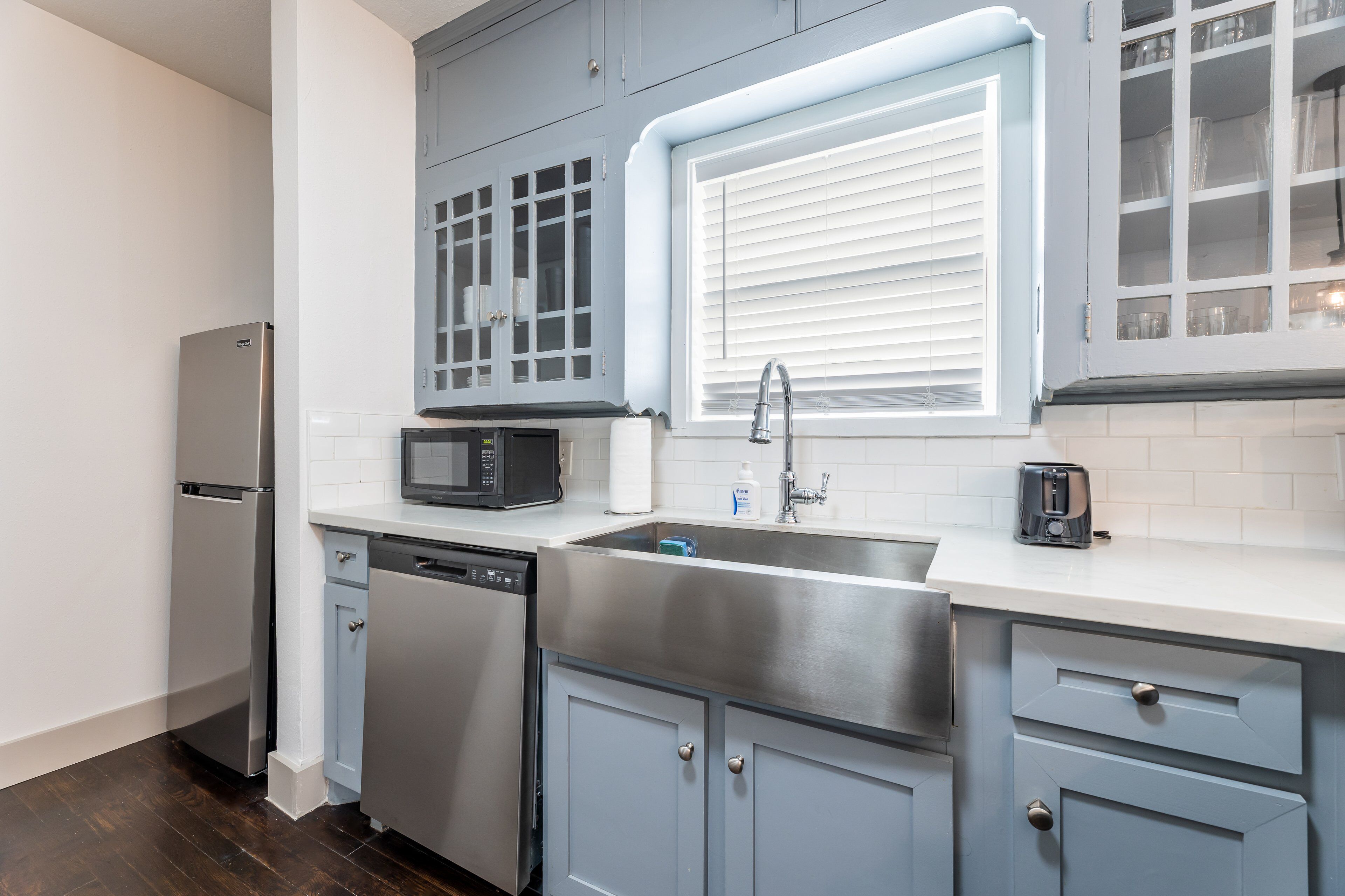 A modern kitchen with grey cabinets, a stainless steel sink, a microwave, and a dishwasher.