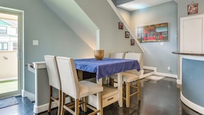 A dining area with a table set for four, a staircase, and a door leading outside. - Houston Retreat With Fireplace & Balcony! (Houston)