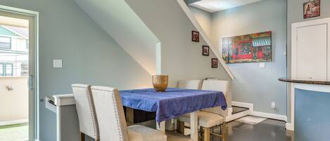 A dining area with a table set for four, a staircase, and a door leading outside.