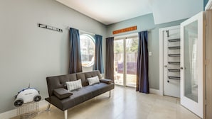 A living room with a sofa, a sign indicating 'Cincinnati Bengals Dr.', and a sliding glass door leading to an outdoor area. - Houston Retreat With Fireplace & Balcony! (Houston)