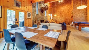 A wooden interior with a stone fireplace, a mounted moose head, and a pool table.