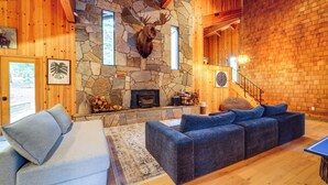 A cozy living room with a stone fireplace, wooden walls, a sofa, and a blue couch.
