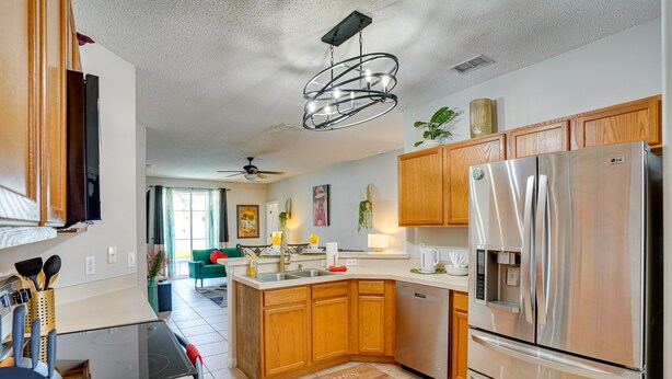 A modern kitchen with wooden cabinets, stainless steel appliances, and a central island. - Florida Retreat w/ Pool, Hot Tub & Near Disney! (Davenport)