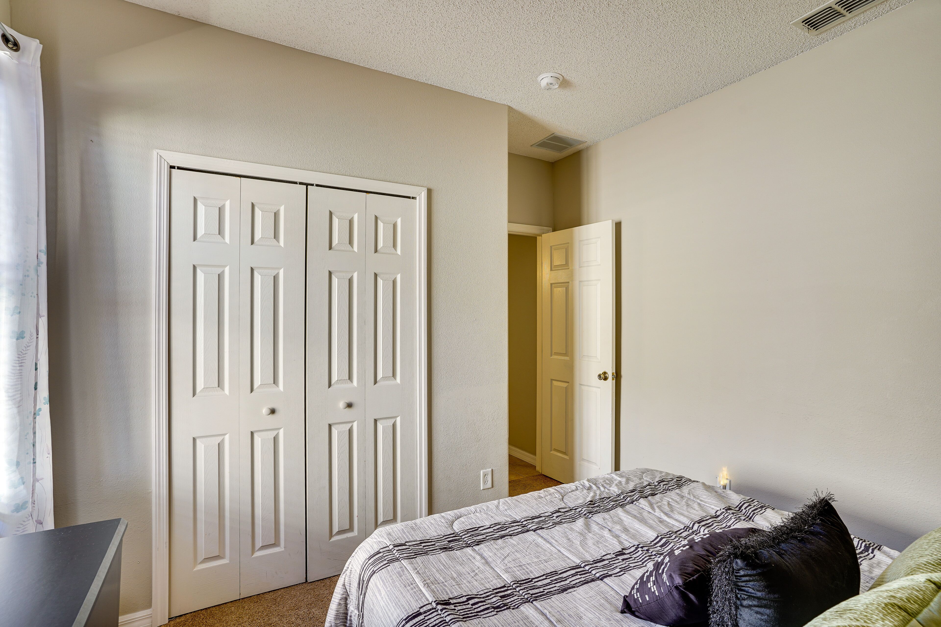 Une chambre à coucher avec un lit, une porte blanche et un couloir menant à une autre pièce.