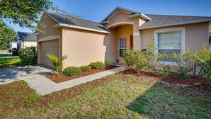 A residential house with a garage, a driveway, and landscaped garden with various plants and shrubs. - Florida Retreat w/ Pool, Hot Tub & Near Disney! (Davenport)
