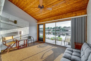 A room with a wooden ceiling, a large sliding glass door to a courtyard, a grey sofa, and a wooden chair. - Waterfront Haines City Vacation Rental w/ Pool! (Haines City)