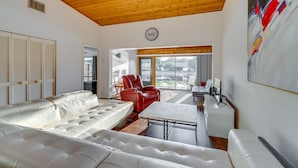 A modern living room with a white leather sofa, a red leather chair, and a small white table. - Waterfront Haines City Vacation Rental w/ Pool! (Haines City)