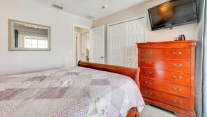 A bedroom with a bed, dresser, television, and a mirror. - Lanai w/ Private Pool! Golf Getaway in Haines City (Haines City)