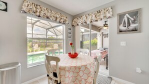 A dining area with a table, chairs, a window with a view of a pool, and a ceiling fan. - Lanai w/ Private Pool! Golf Getaway in Haines City (Haines City)