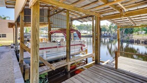 A boat docked at a wooden pier with a covered area overhead.