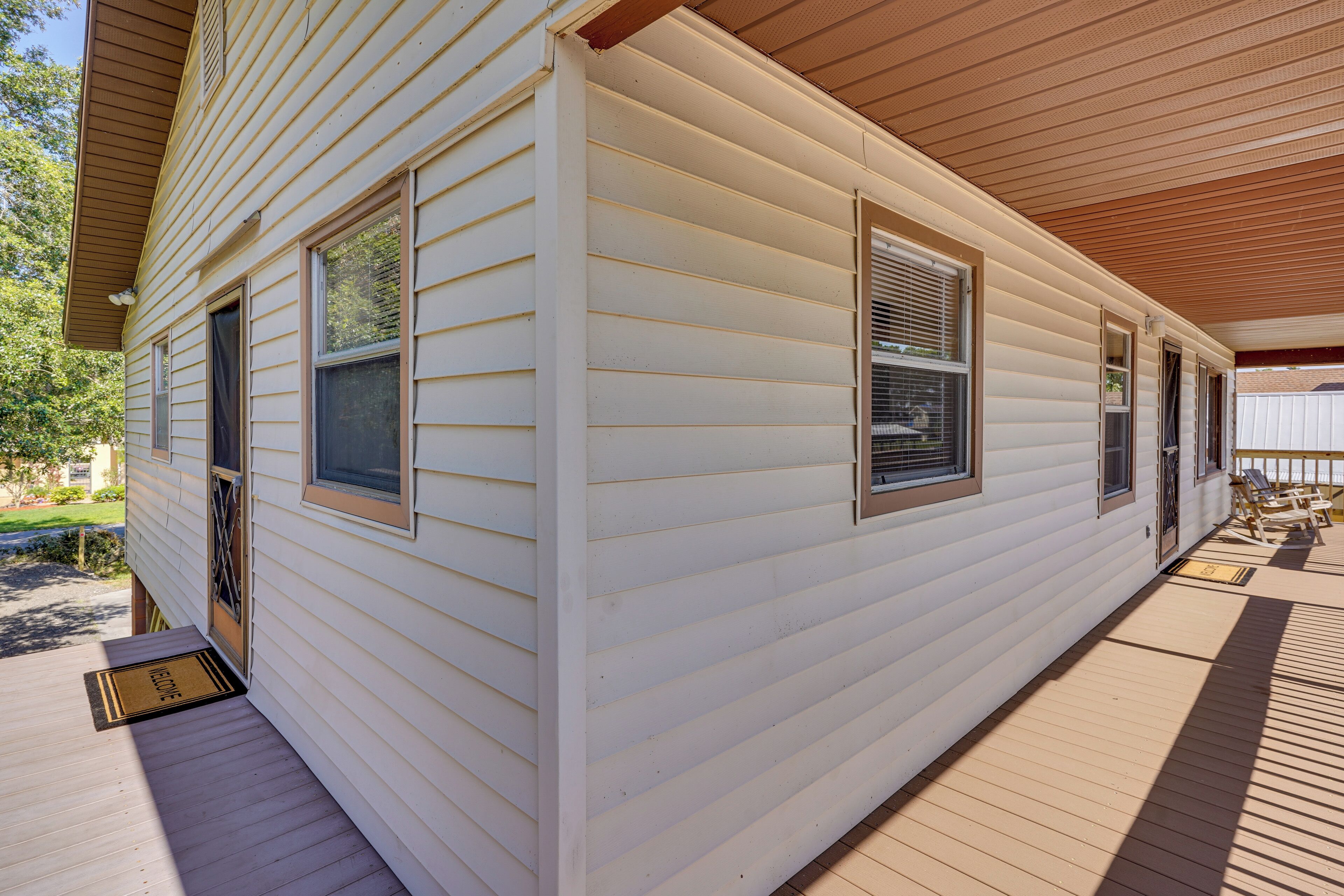 A single-story house with a covered porch, a front door, and two windows with shutters.