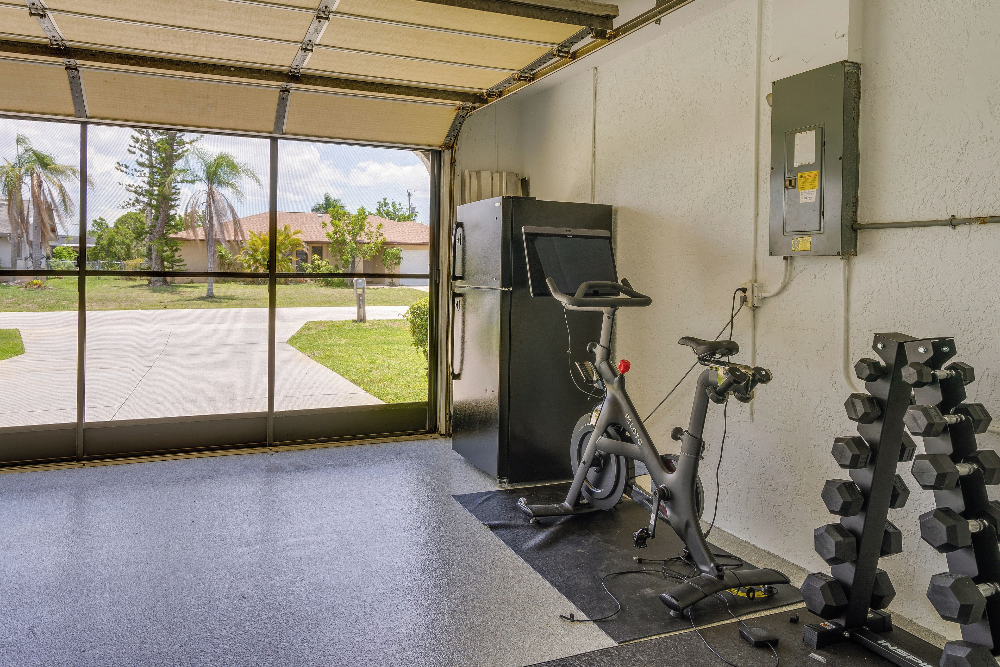 A gym with exercise equipment, a treadmill, and a wall-mounted electrical box.