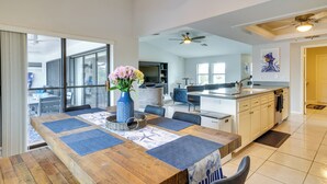 Una cocina amplia con una isla grande, electrodomésticos modernos y un comedor con una mesa de madera y manteles individuales azules.