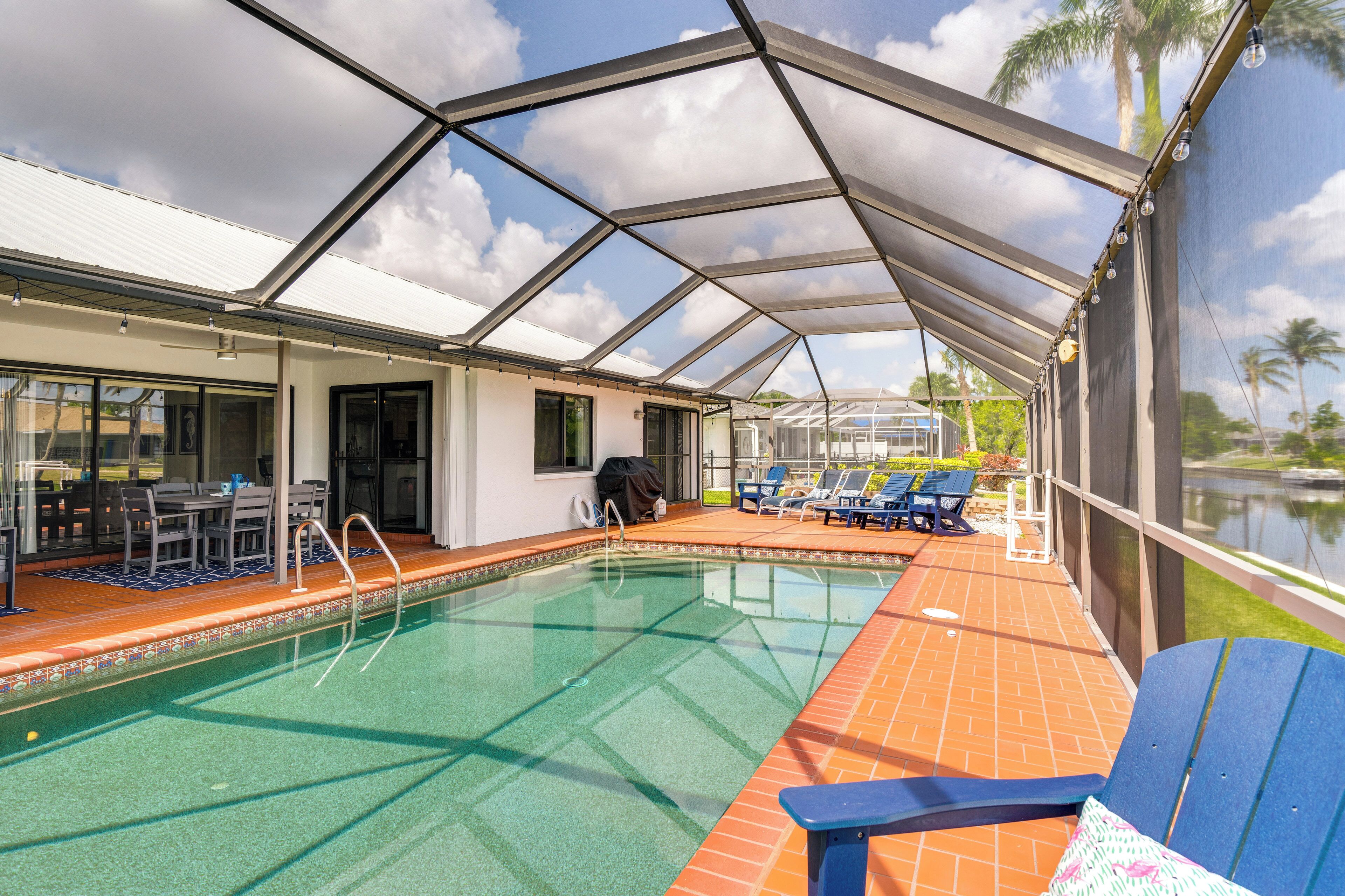 A covered swimming pool with lounge chairs and a barbecue area.