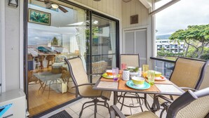 Ein Balkon mit Esstisch, Korbstühlen und Deckenventilator.