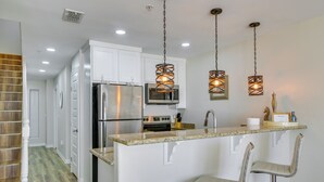 A kitchen with white cabinets, stainless steel appliances, and a granite countertop. - South Padre Island Condo: Walk to the Beach! (South Padre Island)