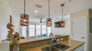 A kitchen with granite countertops, a stainless steel sink, and pendant lights. - South Padre Island Condo: Walk to the Beach! (South Padre Island)
